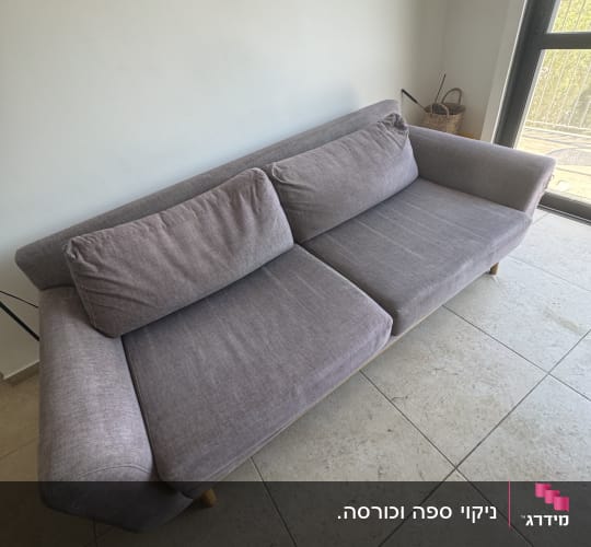 ספת בד אפורה נקייה ומורפדת בסלון הבית